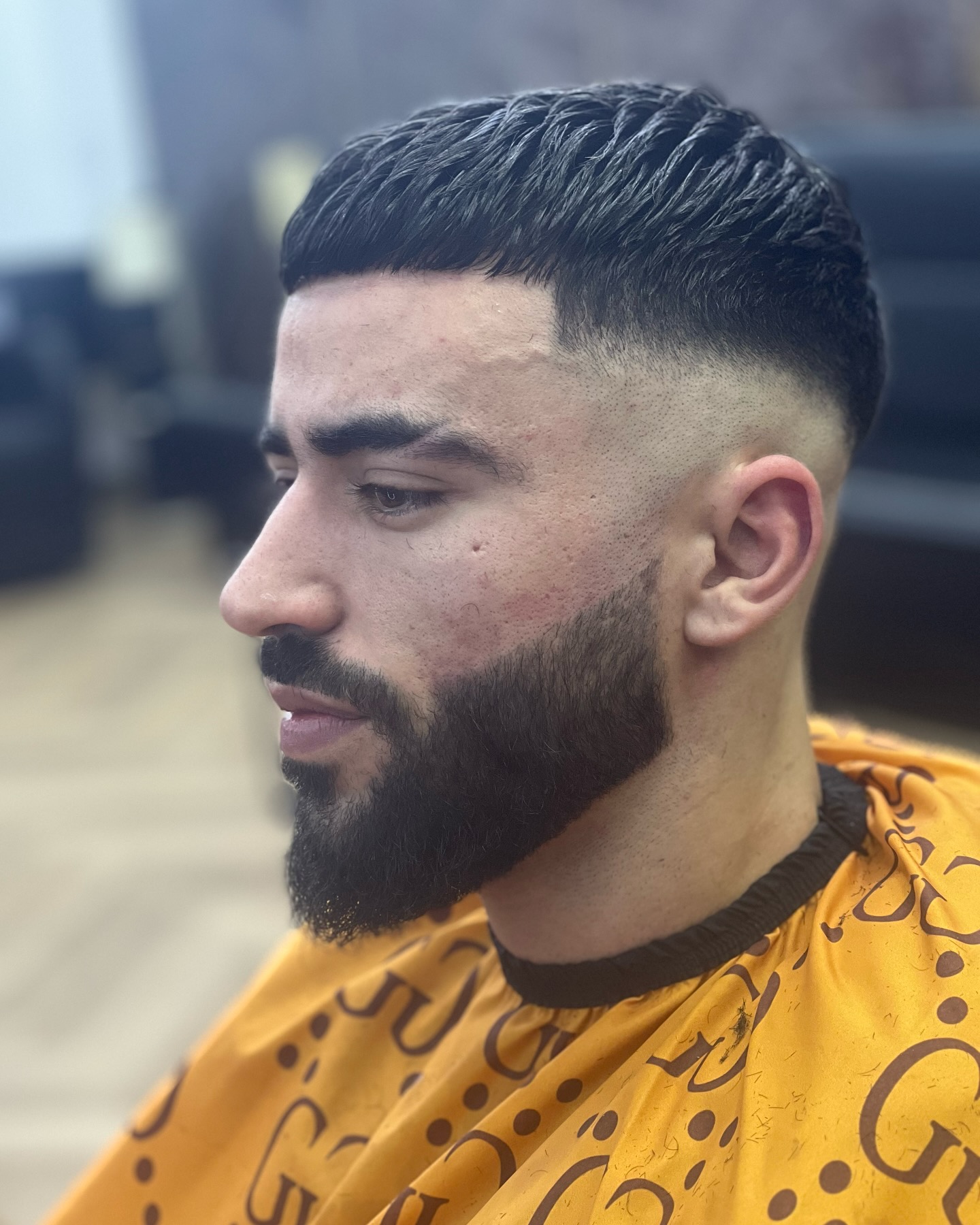 Klant met een donkere fade, strakke line-up en volle baard